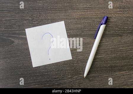 A pen and a leaf with a question mark lie on the office table Stock Photo