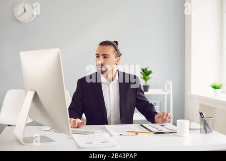Businessman in a black jacket works. Analyzes at the computer in the office. Stock Photo