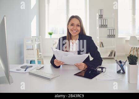 Happy businesswoman with documents in hands sitting at table Stock Photo