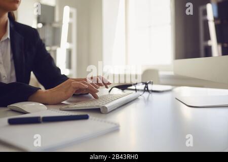 Busy faceless worker is typing at workplace using computer in office. Stock Photo