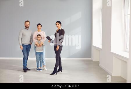 Real estate agent woman smiling with clipboard and family in new home Stock Photo