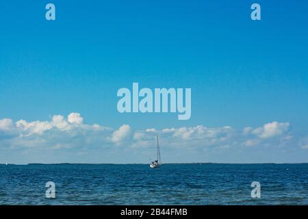 Sailboat cruising through the ocean in a clear cloudy sky. Stock Photo