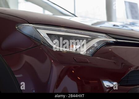 New vehicle of cherry color with elegant head lamps in showroom. Side view. Stock Photo
