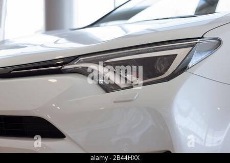 New white vehicle with elegant head lamps in showroom. Side view. Stock Photo