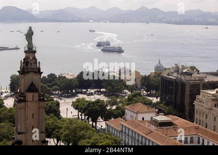 Port area with the Imperial palace cultural centre and Dom João VI monument in the foreground and ferry boats to and fro from Niteroi in the back Stock Photo