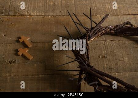 Close-up of two small wooden crosses and a representation of the crown of thorns of Jesus Christ on a wooden surface Stock Photo