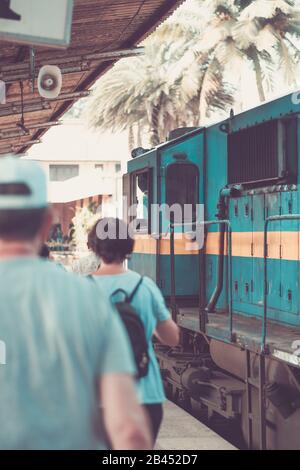 Train on station and People locals and tourists go on 1 track of the railway station platform in Galle Sri Lanka Stock Photo