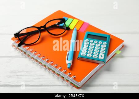 Copybook, glasses, calculator, pen and stickers on wooden background, close up Stock Photo
