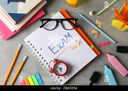 Inscription Exam and different stationary on grey background, top view Stock Photo