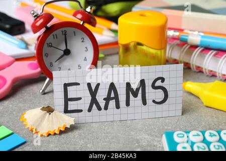 Inscription Exams and different stationary on grey background, closeup Stock Photo