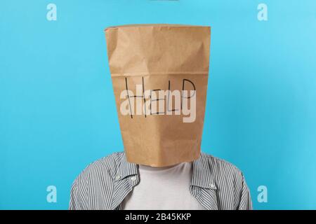 Person with paperbag on head with inscription Help on blue background Stock Photo