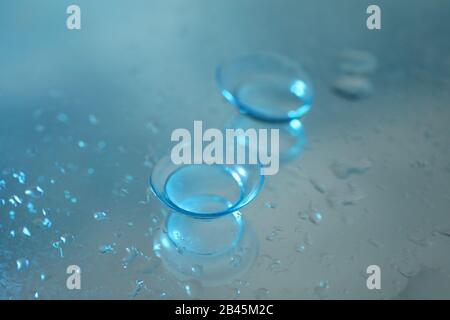 Contact lenses on mirror surface with water, close up Stock Photo