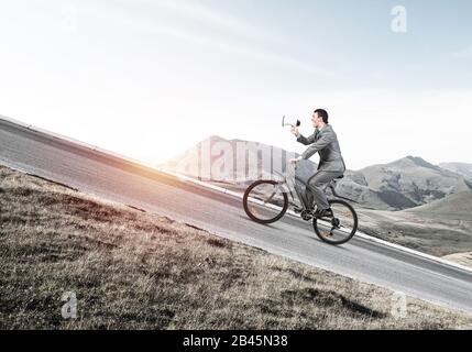 Businessman with megaphone in hand on bike Stock Photo