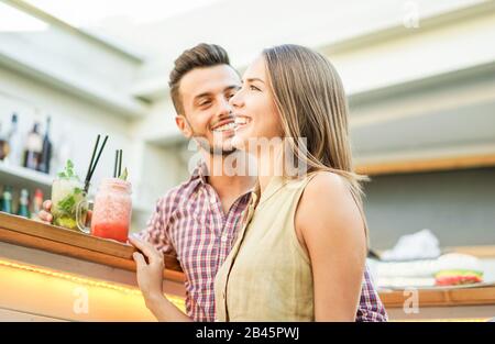 Handsome couple laughing and toasting cocktails in lounge disco bar - Young people having fun hanging out - Party, relationship and happy hour concept Stock Photo