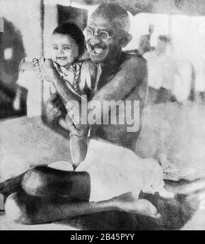 Mahatma Gandhi laughing playing with a child during his voyage on SS Rajputana, British passenger ocean liner, September 1931, old vintage 1900s picture Stock Photo