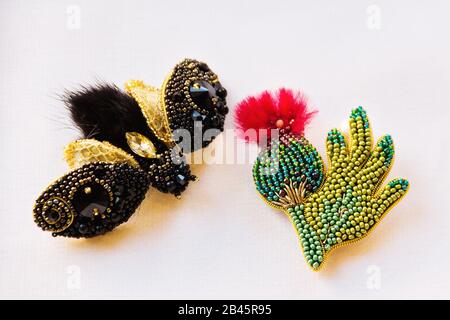 Homemade crafts made of beads on a white background. Homemade butterfly and thistle. Stock Photo