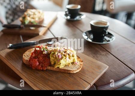 Single piece of italian baguette with cheese pasta toppings and red tomato sauce served with coffee in cafe