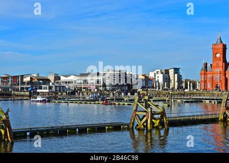 A view across Cardiff Bay towards Mermaid Quay development of shops, bars & restaurants. Red brick Pierhead Building on far right. Stock Photo