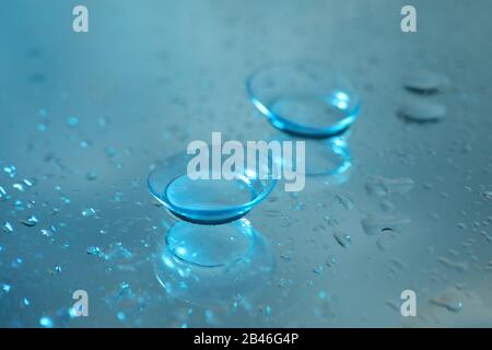 Contact lenses on mirror surface with water, close up Stock Photo
