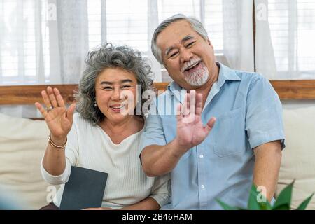 Asian couple Grandparent greeting and talking with Granddaughter with happy feeling via video phone call by mobile phone in house, Long live and Elder Stock Photo