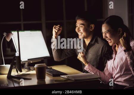 Asian business woman and business man working hard late together with technology computer in office,team work with colleagues to congratulations for s Stock Photo