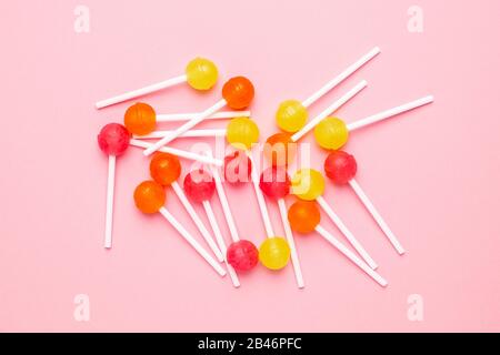 Pink, orange and yellow sweet candy lolipop on a pastel pink background top view. Stock Photo