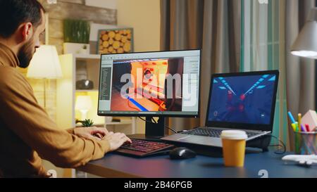 Male game developer typing on keyboard while developing a new level of the game. Stock Photo
