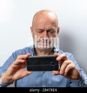 A middle-aged man takes a photograph with his cell phone Stock Photo