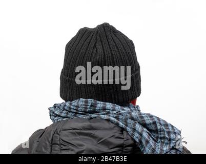 A middle-aged man turned from the back with his jacket,  scarf and cap Stock Photo