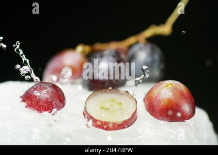Bunches of grapes in ice water with colorful flashes photographed in studio Stock Photo