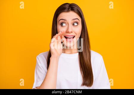 Photo of chatterbox pretty lady long hairstyle say tell news arm near mouth look sly side empty space gossip girl wear casual white t-shirt isolated Stock Photo