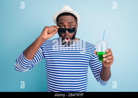 Photo of excited shocked dark skin guy traveler hold green alcohol beverage cup taking off specs see attractive girl wear white sun cap striped sailor Stock Photo