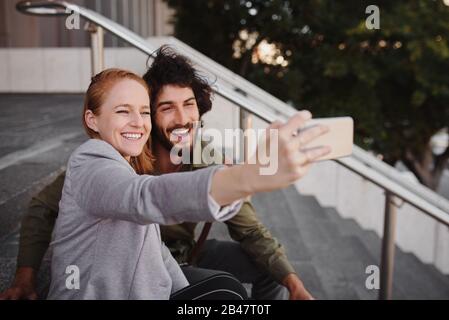 Happy professional couple taking selfie using smartphone during break Stock Photo