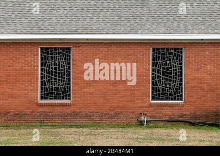 a pair of stained glass church windows on a red brick wall Stock Photo