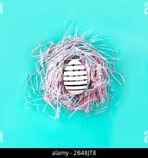 Graphic hand-painted in line egg in decorative nest on blue pastel background. Easter concept. Stock Photo