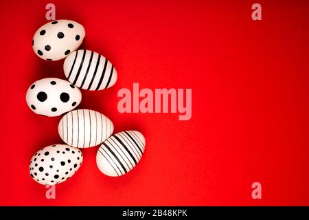 Different graphic hand-painted eggs on bright red background. Easter concept. Place for text. Stock Photo