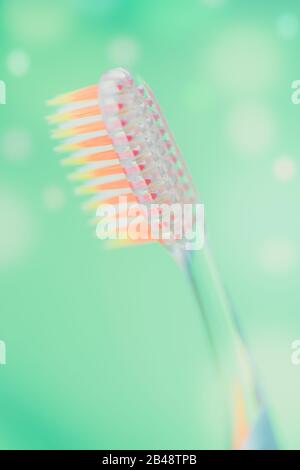 Orange plastic toothbrush on a green background with soap bubbles. Stock Photo