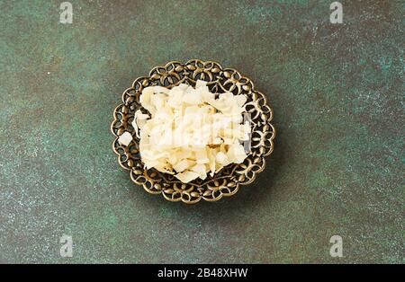 Organic Roasted coconut chips in a arabic bowl on a green background. Stock Photo