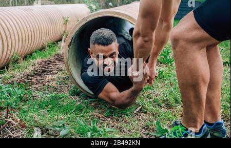 Participants obstacle course going through a pipe Stock Photo