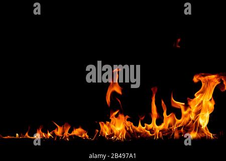On fire flames at the black background, Burning red hot sparks rise, Fiery orange glowing flying particles Stock Photo