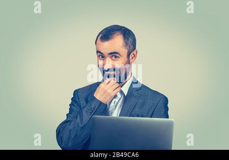 Thoughtful business man with laptop computer looking at you camera. Closeup portrait of Mixed race bearded model Latin American guy isolated light gre Stock Photo