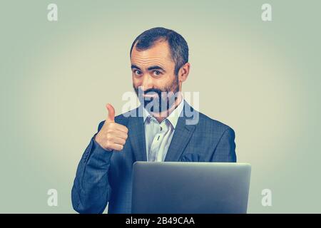 Portrait handsome smiling businessman working at laptop outdoors giving thumbs up. Closeup portrait of Mixed race bearded model Latin American guy iso Stock Photo