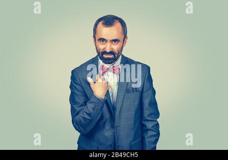 Closeup portrait unhappy annoyed mature bearded man, getting mad asking question you talking to me, do you mean me? Isolated green wall background. Ne Stock Photo
