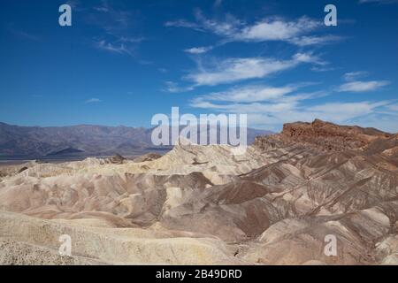 Panoramic view of Zabriskie Point, Death Valley National park, with arid rocks in the shape of waves in the foreground and mountains in the background Stock Photo