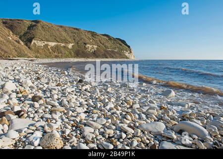 Landscape coastal scene of large stony pebble beach with chalks cliffs coastline dropping into sea Stock Photo