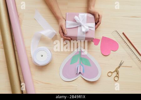 Horizontal from above flat lay composition of cards, decorations and hands holding gift box for Mother's Day Stock Photo