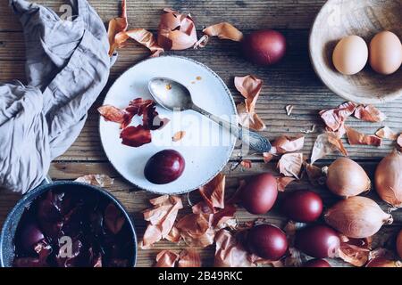 Dyed Easter eggs painted with natural dye onion on rustic wooden background. Process of dyeing eggs with natural paints for Easter. Natural ecological Stock Photo