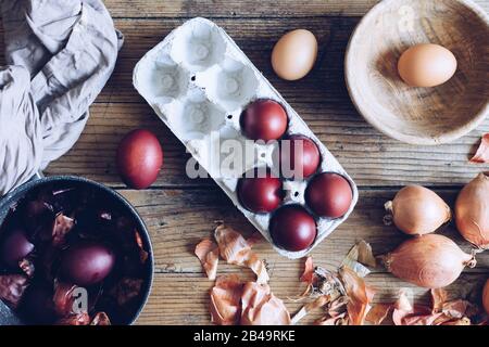 Dyed Easter eggs painted with natural dye onion on rustic wooden background. Process of dyeing eggs with natural paints for Easter. Natural ecological Stock Photo