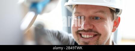 Young repairman in helmet, gloves and special uniform repairing house details Stock Photo