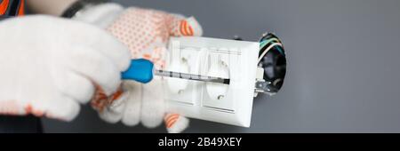 Repairman in gloves fixing socket with screwdriver Stock Photo